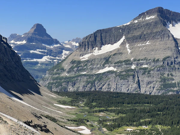 A snow-streaked peak above a green valley in Glacier National Park