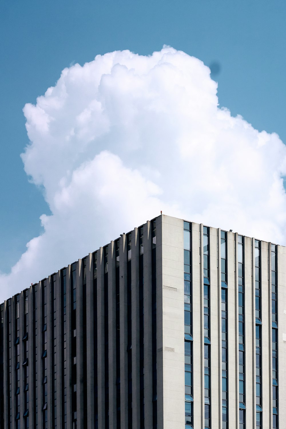 a tall building with a cloud in the sky above it