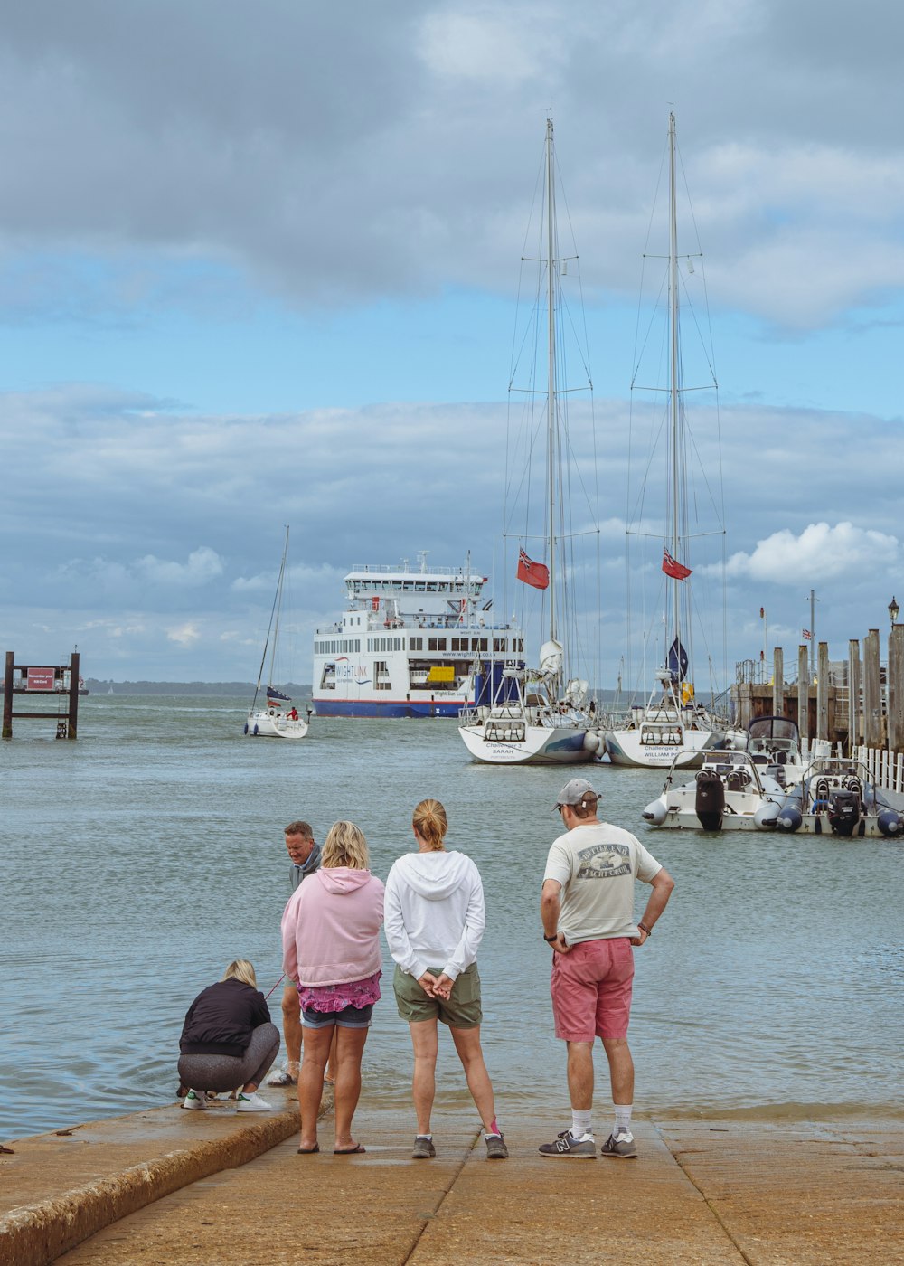 a group of people standing on a dock looking at a large sailboat