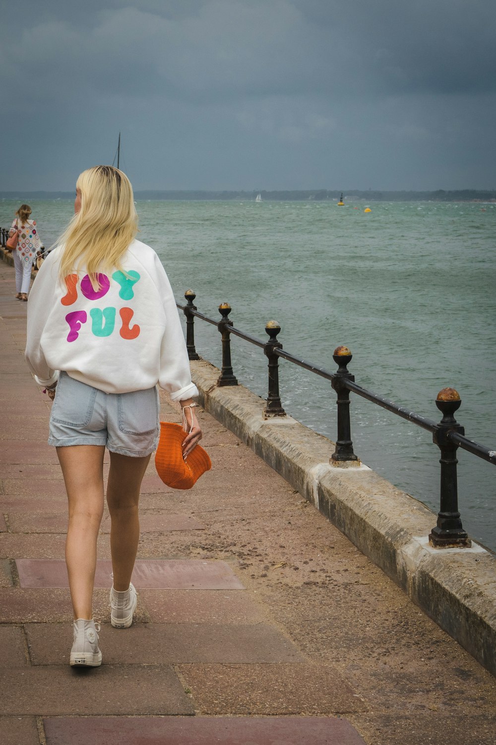 a woman walking on a sidewalk near the water