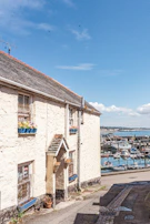 A charming waterfront cottage with vibrant flower boxes under bright blue skies.