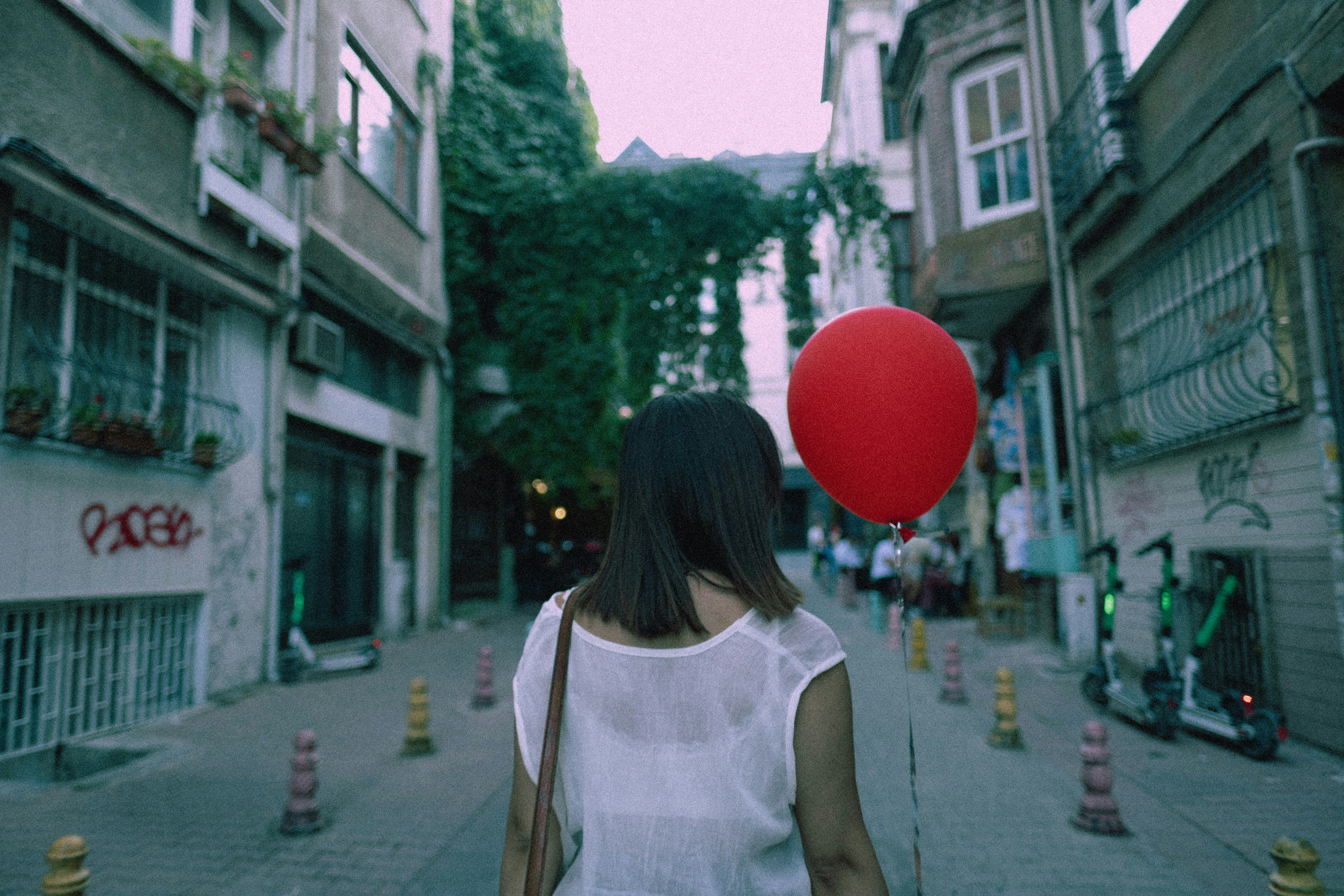 a woman walking down a street with a red balloon in her hand