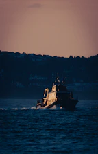 Modern maritime vessel navigating calm open waters at sunset.