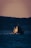 Image of a ship navigating through calm waters during sunset.