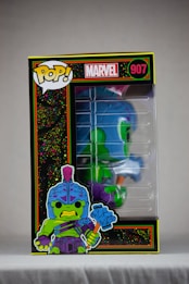 A Funko Pop! collectible figure encased in a box with vibrant illustrations and branding. The character depicted is green with a blue helmet and armor, wielding a large hammer. The box features the Marvel logo and the number 907.