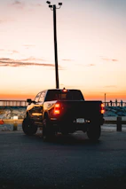 Coastal Clear Junk Removal truck parked by the shore with a sunset backdrop.