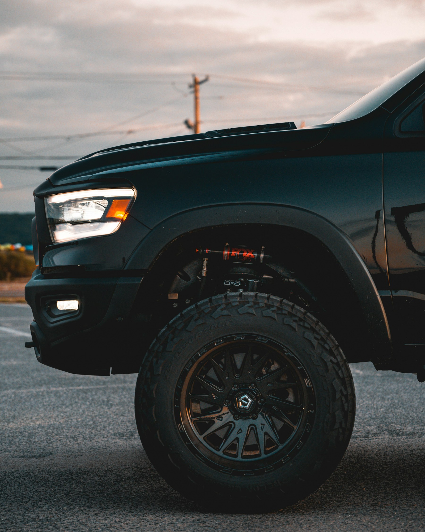 Close-up of a black lifted pickup truck’s front wheel and off-road tire