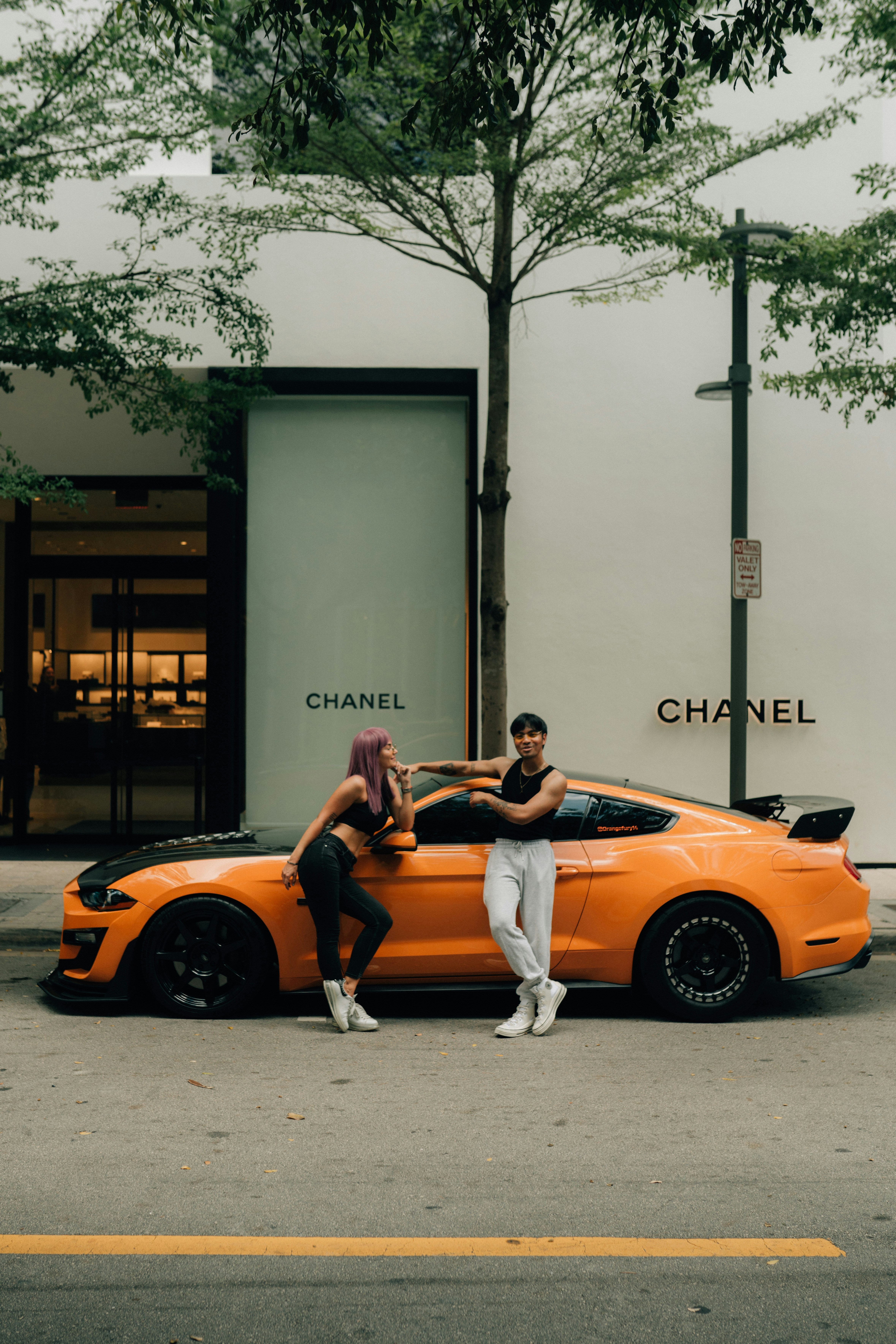 a man and woman posing in front of a yellow car