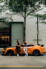 a man and woman posing in front of a yellow car