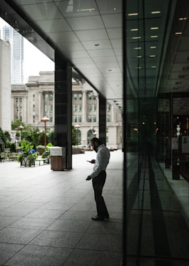 A stylish man using a smartphone in a modern urban setting.