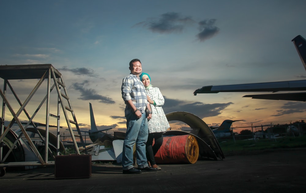 a man and woman standing in front of a plane