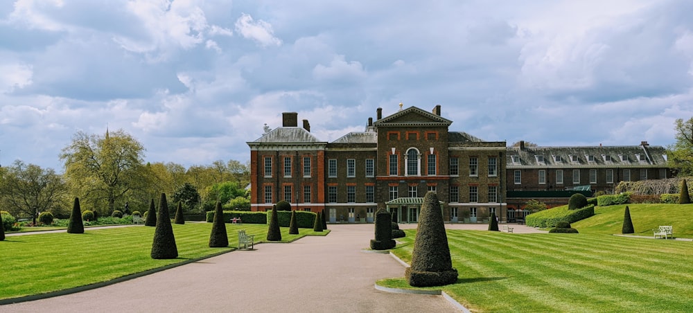 un gran edificio con un césped frente a él con el Palacio de Kensington al fondo