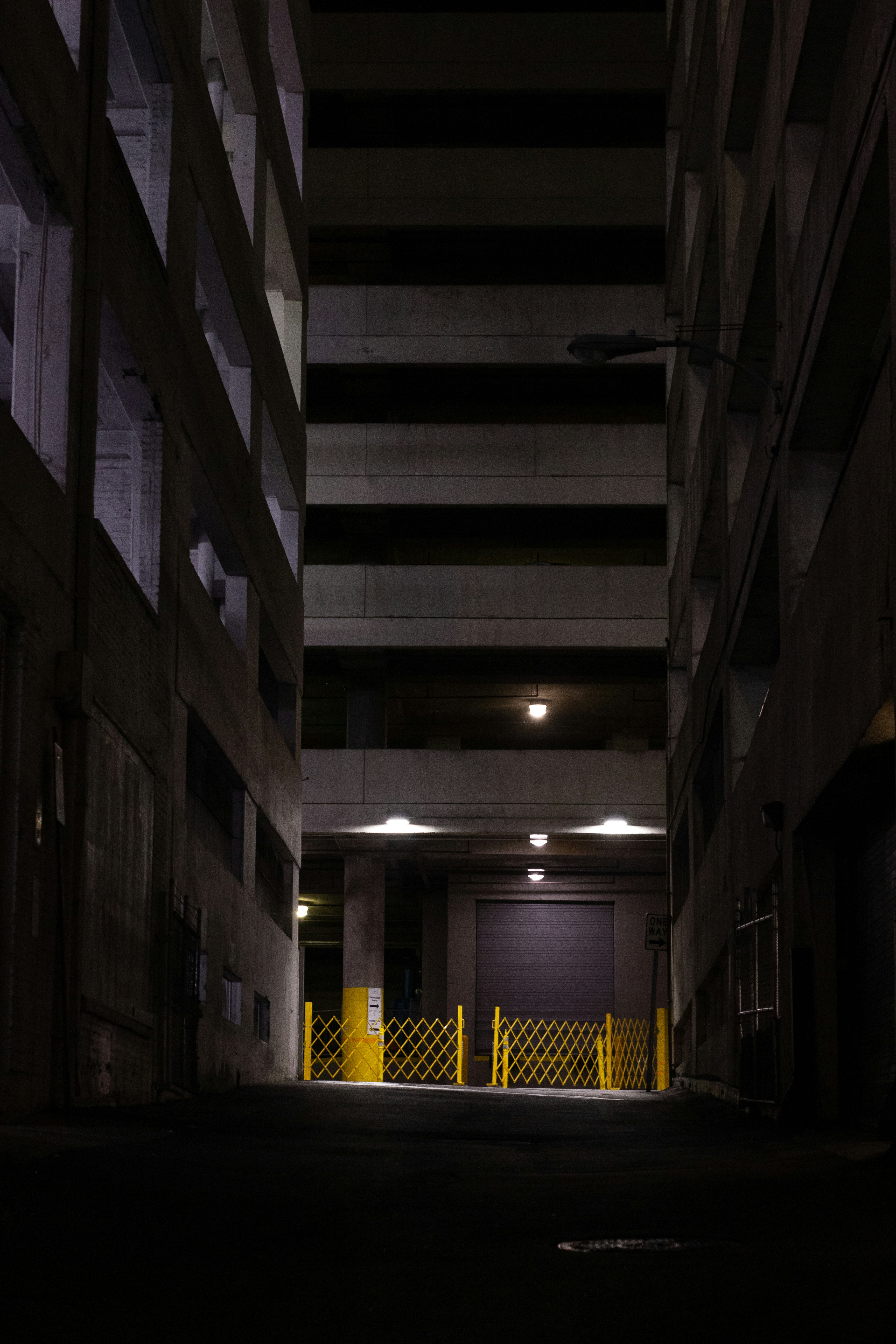 a dark alley way with a yellow fence and a gate