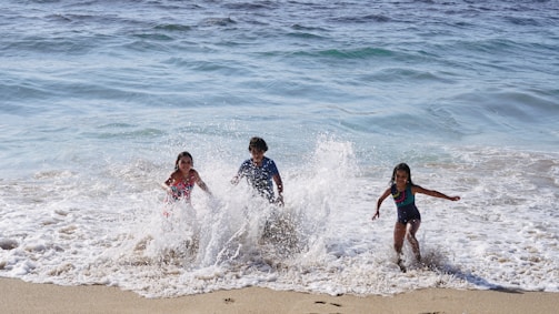 A joyful family playing on a sunlit beach with waves gently rolling in.
