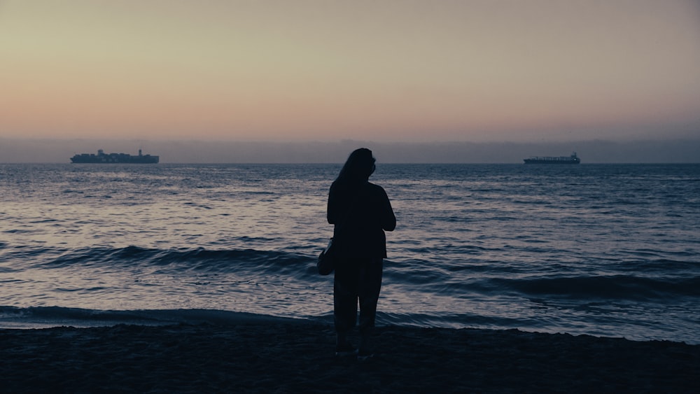 a man standing on a beach looking at the ocean