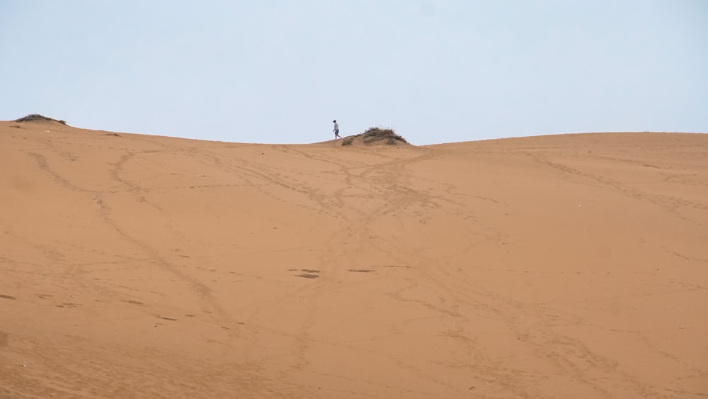 a person walking on a sandy hill