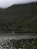 A peaceful moment of a lone paddler sitting on their board, soaking in the morning mist over the lake