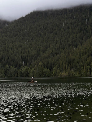 A peaceful moment of a lone paddler sitting on their board, soaking in the morning mist over the lake