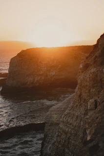 The sun dipping behind the caldera, casting golden light over the volcanic cliffs