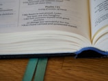 An open book with visible text from Psalm 131, featuring blue stitching along the spine and two green bookmarks underneath. The pages appear slightly yellowed, indicating a well-used or aged book.