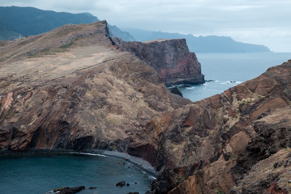 a rocky cliff next to a body of water