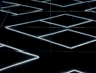 A sleek neon geometric pattern glowing against a black carbon background.