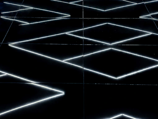 A sleek neon geometric pattern glowing against a black carbon background.