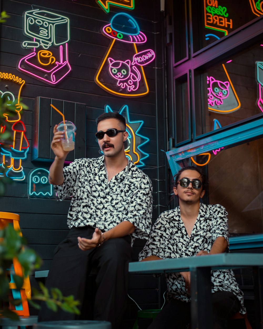 a man and woman sitting on a bench in front of a building with neon signs