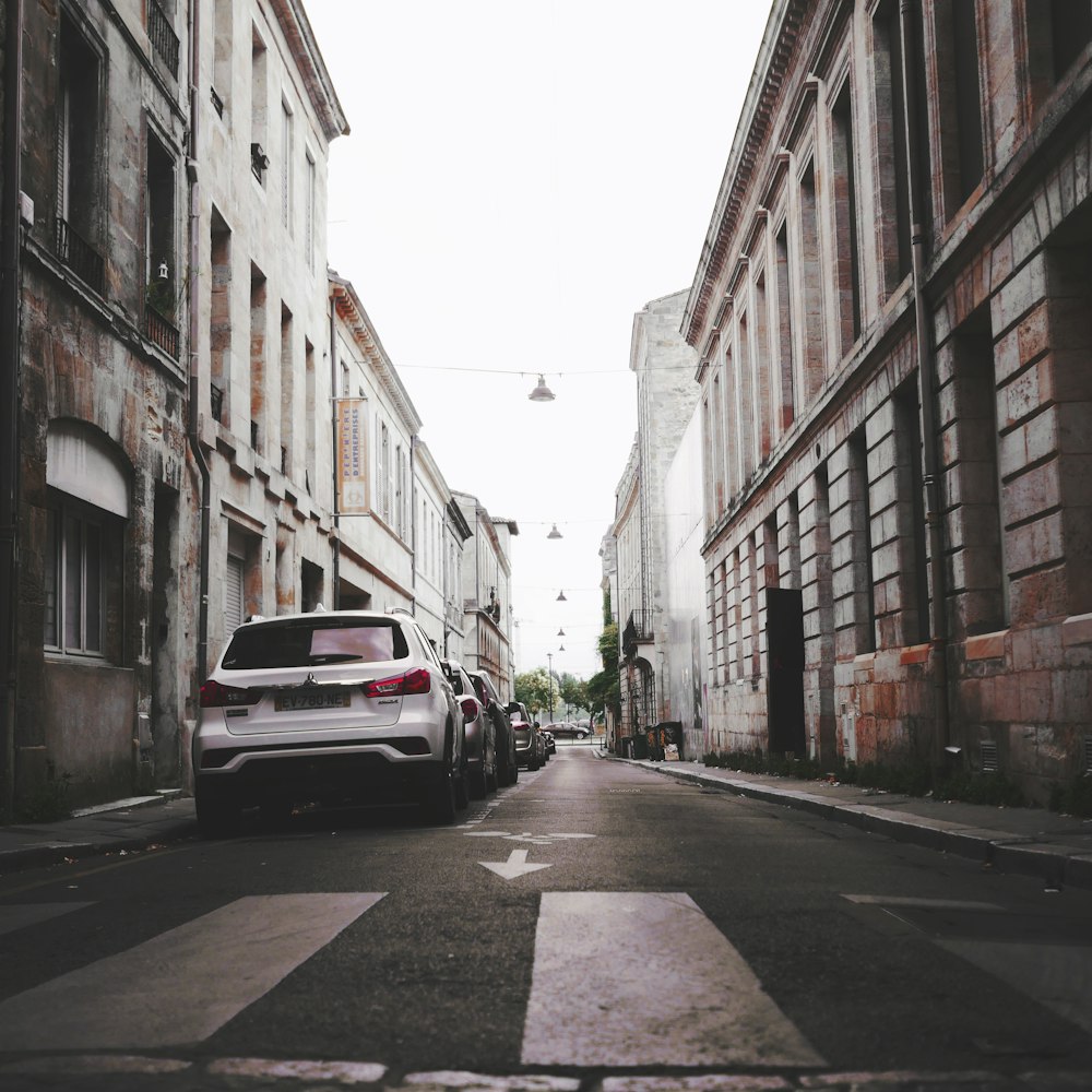 a car parked on the side of a street between buildings