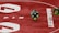 Two green dice with rounded edges are positioned on a red surface that seems to be part of a game board. The surface has white text and numbers on it, including the word 'LUCKYTOPSPIN' in capital letters.