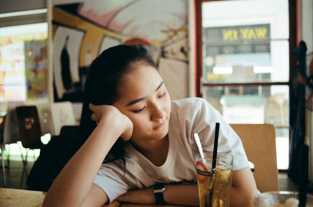 a person sitting at a table with a drink in the hand