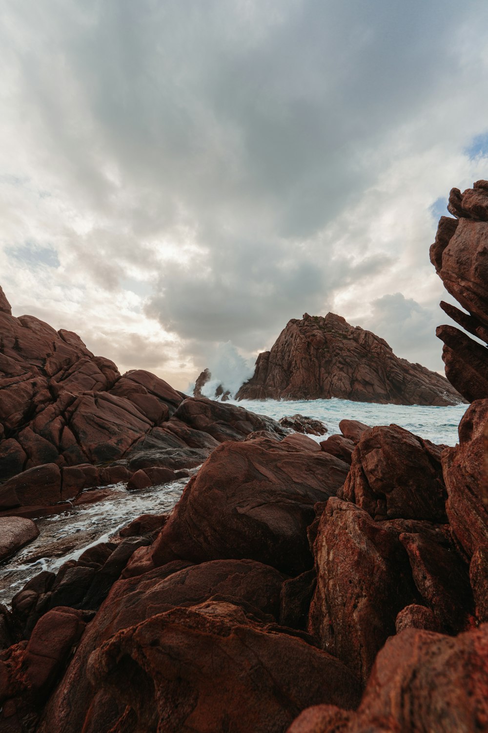 a rocky beach with a body of water in the background