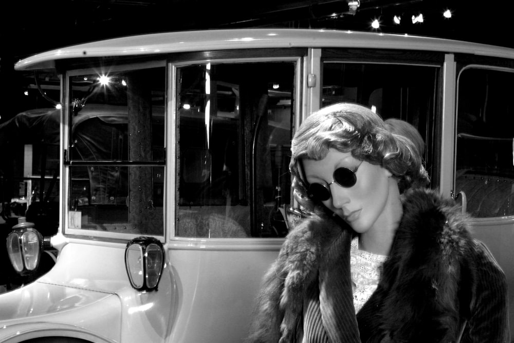 a person in a fur coat and sunglasses leaning on a bus