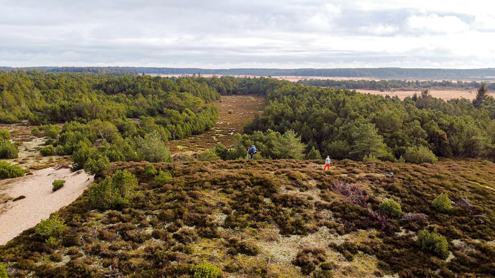 a group of people walking on a dirt path in a hilly area