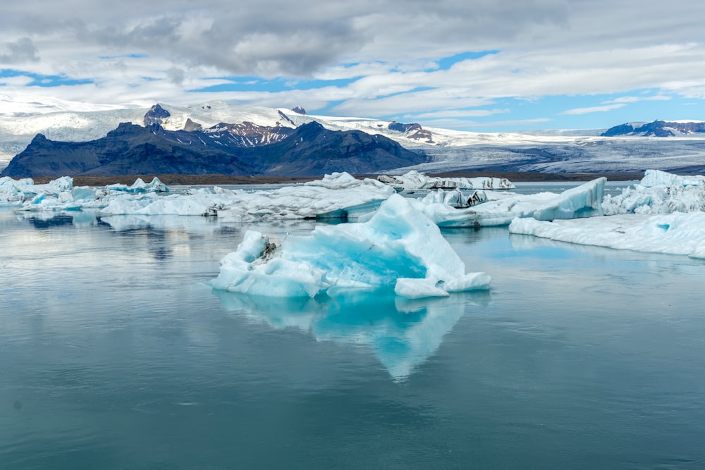 a body of water with icebergs and mountains in the background