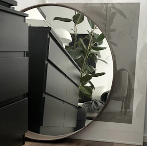 A sleek, modern minimalist dressing table with clean lines and a soft matte finish, styled with a small vase and a round mirror.