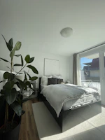 A bright bedroom featuring a plush bed with crisp linens and a large window letting in natural light.