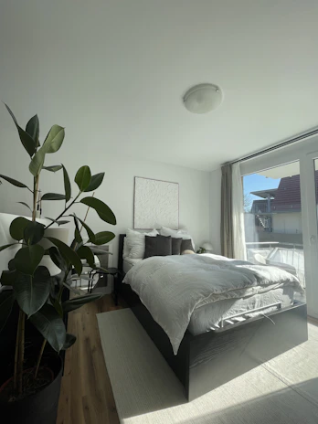 Spacious modern apartment bedroom with natural light and soft linens.