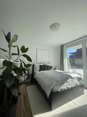 A bright bedroom featuring a plush bed with crisp linens and a large window letting in natural light.