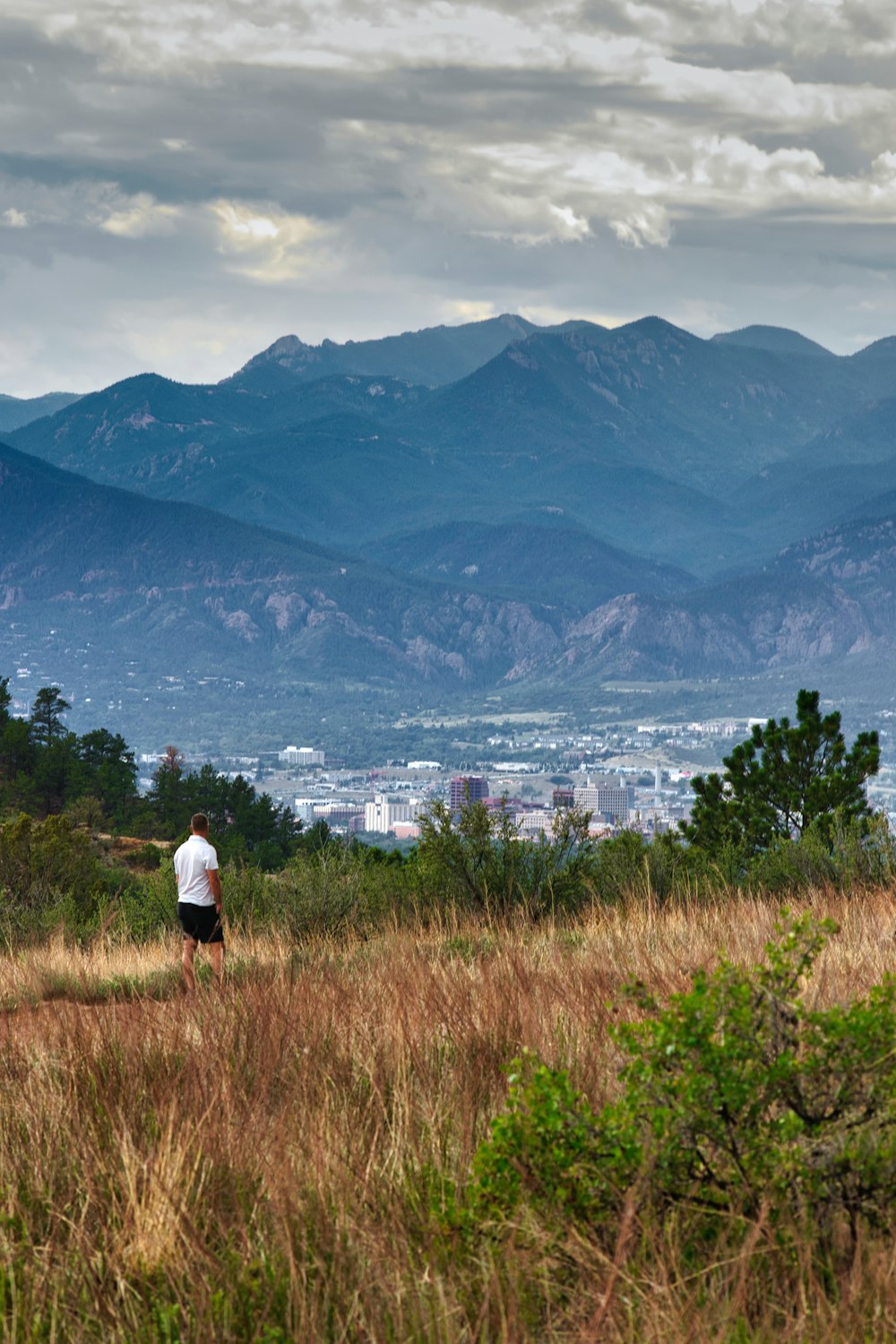 a person standing on a hill overlooking a city and mountains