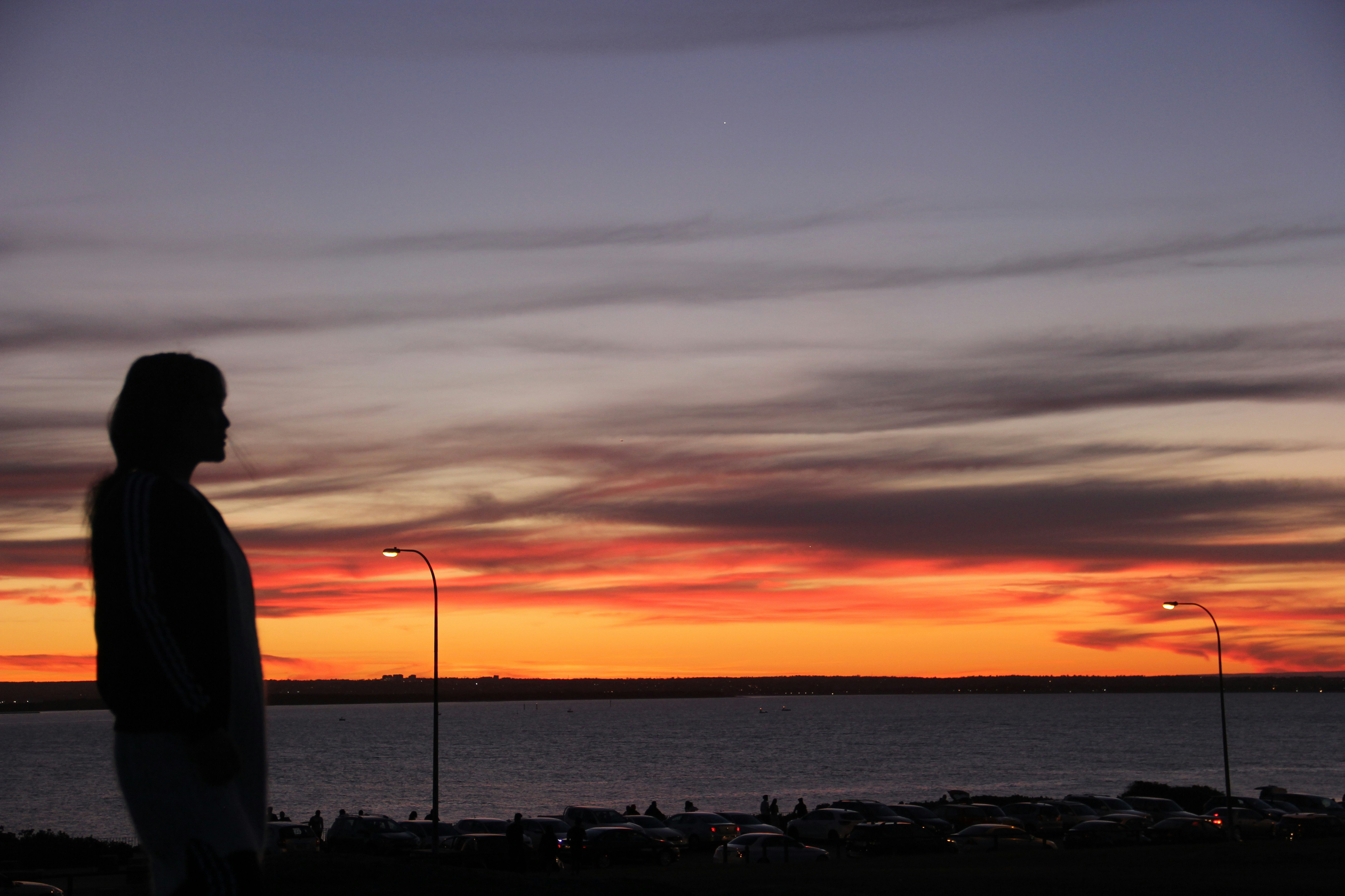 a person standing on a beach looking at the sunset