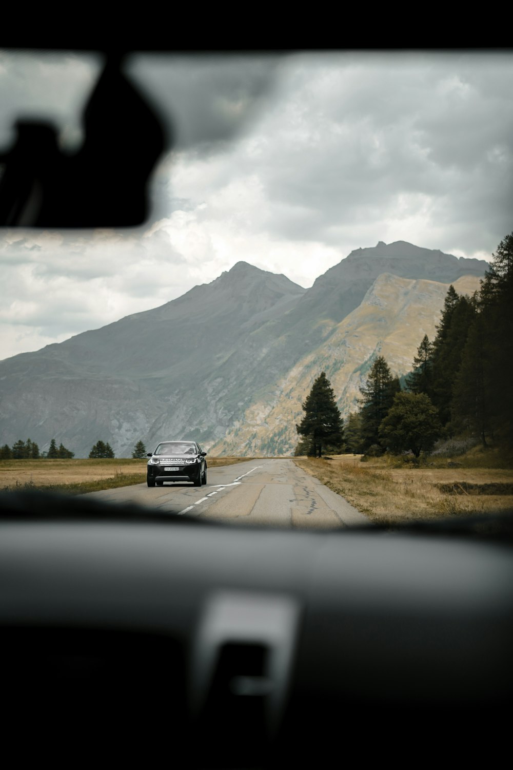 a car driving on a road with mountains in the background