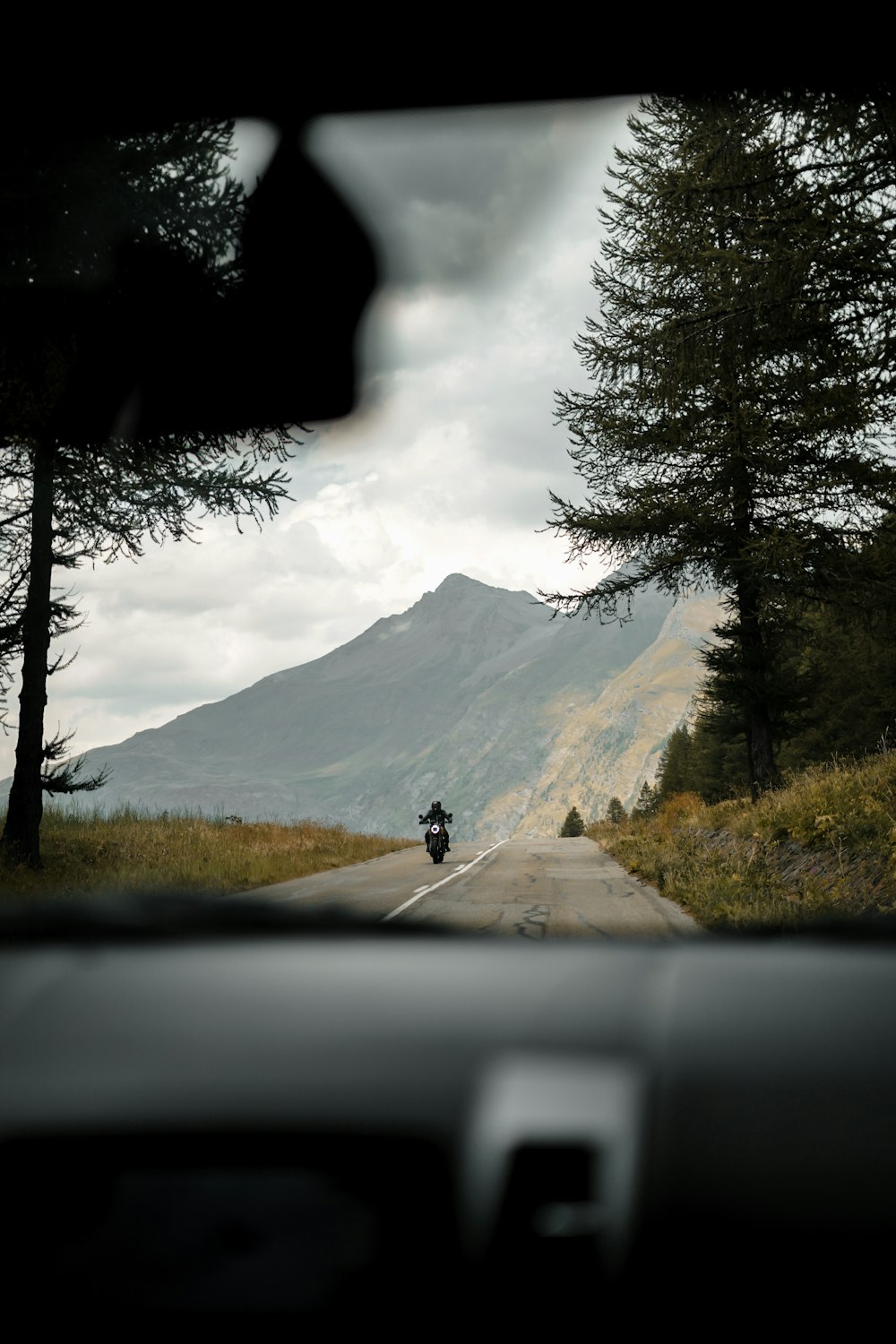 a person riding a motorcycle on a road with trees on either side