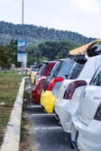 A row of diverse vehicles parked in a sunny lot.