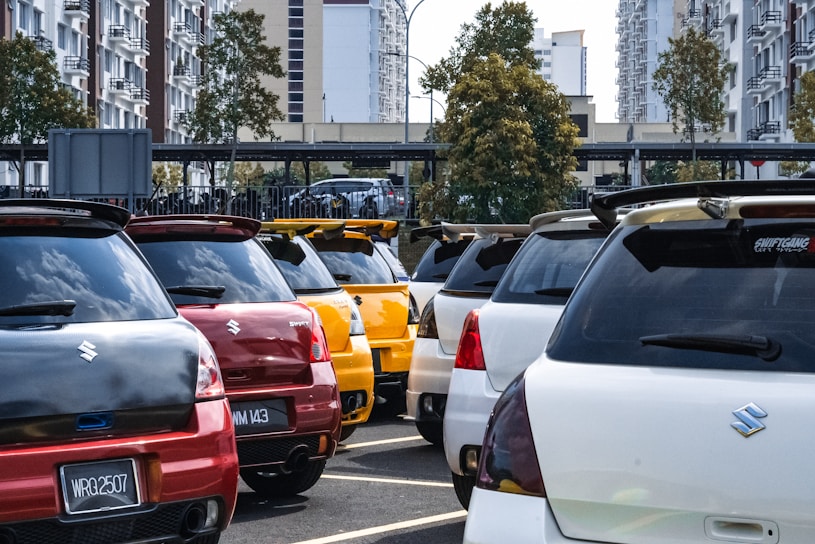 Front view of a shiny Suzuki car parked outside the Suzuki Neiva dealership on a sunny day.