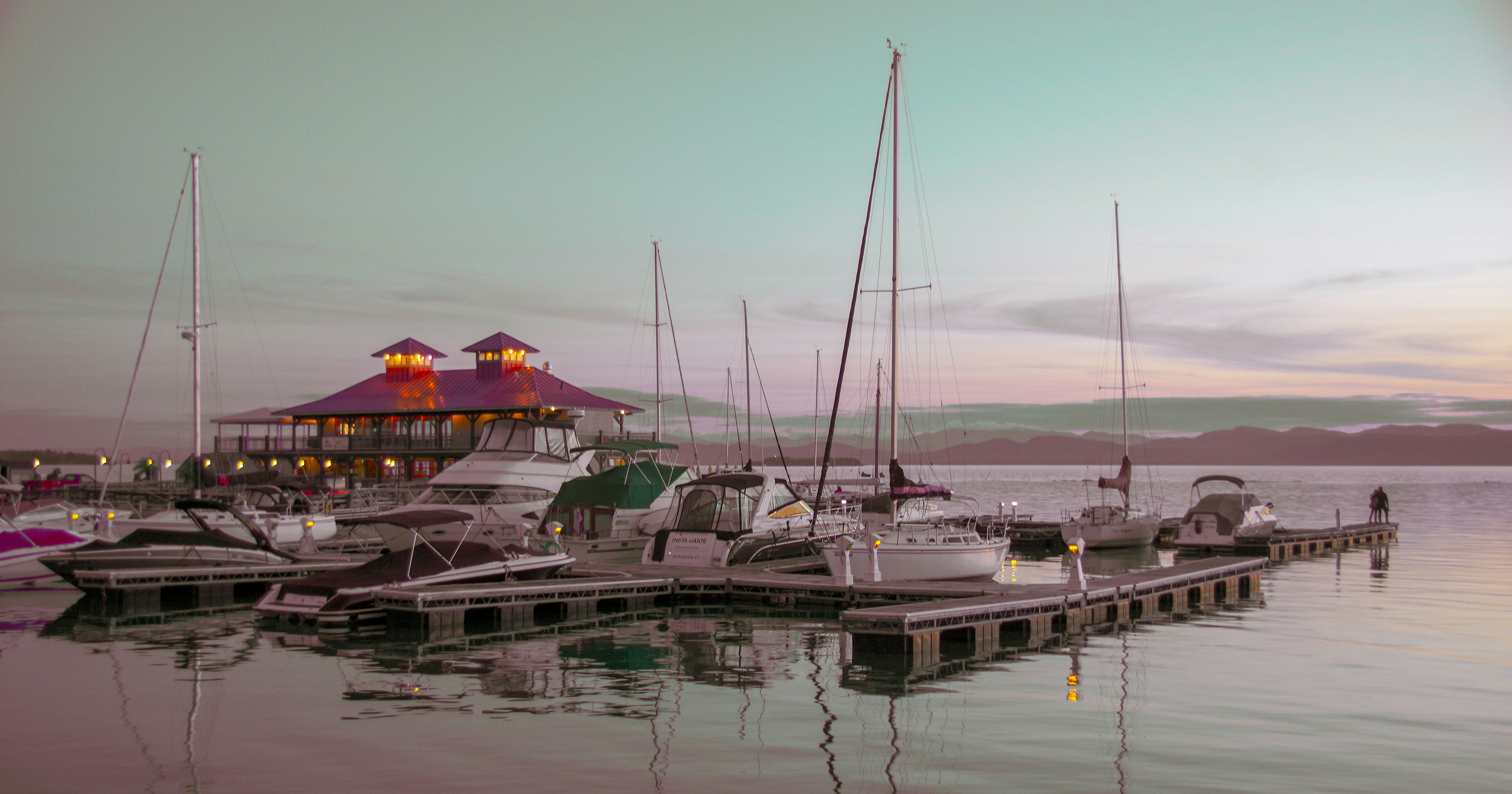 a group of boats sit on a dock, The Burlington (VT) Boathouse on Lake Champlain at sunset. 