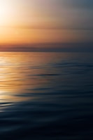 a large body of water with a sunset in the background