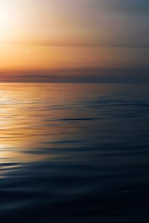 a large body of water with a sunset in the background