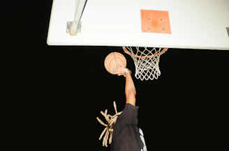 Action shot of Mazzi mid-air dunk during a high school basketball game.