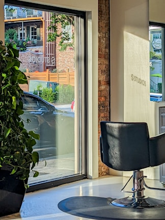 Cozy salon chair bathed in soft natural light next to a large window with greenery outside.